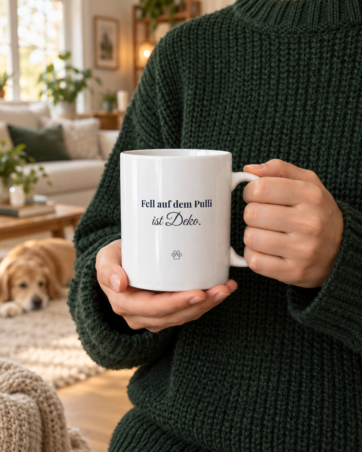 Weiße Tasse mit dem Spruch „Fell auf dem Pulli ist Deko.“, gehalten von Händen im Strickpulli