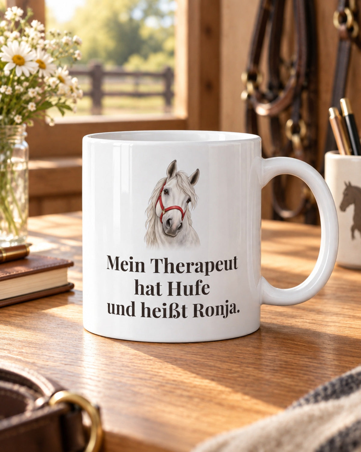 Weiße Tasse mit Schimmelkopf und Spruch Mein Therapeut hat Hufe und heißt Ronja, auf einem Holztisch in der Sattelkammer