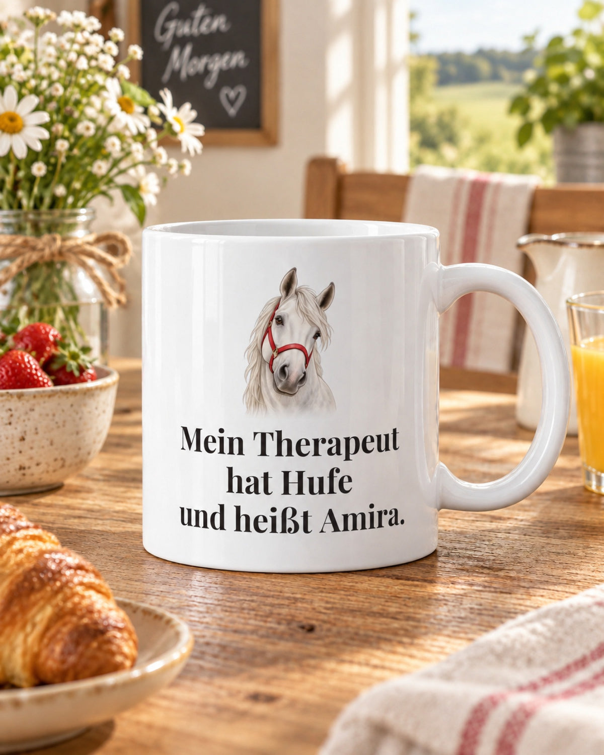 Weiße Tasse mit Schimmelkopf und Spruch Mein Therapeut hat Hufe und heißt Amira, auf dem Frühstückstisch mit Croissant und Erdbeeren