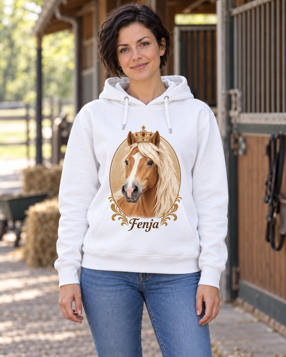 Frau vor dem Pferdestall im weißen Hoodie mit Haflinger Fenja im Royal-Stil mit Krone auf der Brust