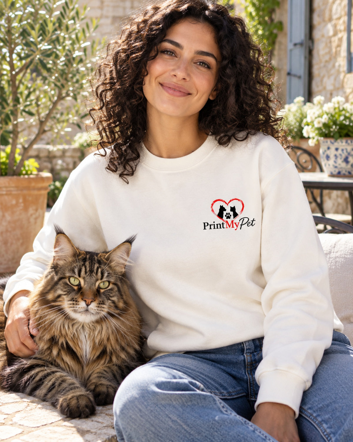 Frau im weißen Sweatshirt mit schwarz-rotem PrintMyPet-Logo auf der Brust und ihrer Katze