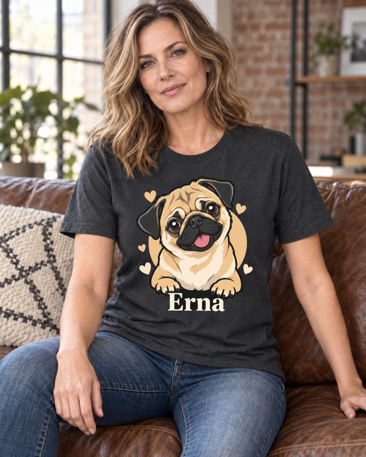 Frau auf dem Ledersofa trägt ein dunkelgraues T-Shirt mit Mops Erna im Cartoon-Stil mit Herzen