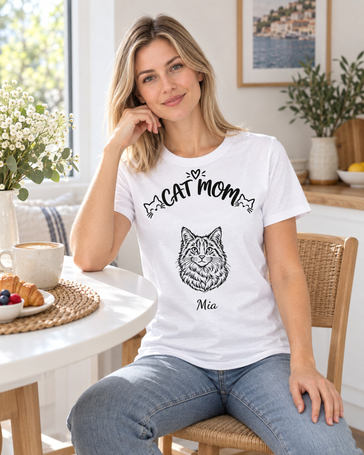 Frau im weißen T-Shirt „Cat Mom“ mit Katzenzeichnung und Namen Mia am Frühstückstisch