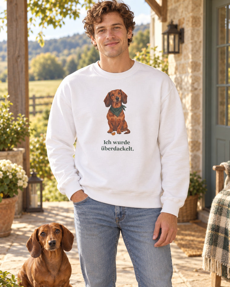 Mann im weißen Sweatshirt „Ich wurde überdackelt.“ mit seinem Dackel vor dem Haus