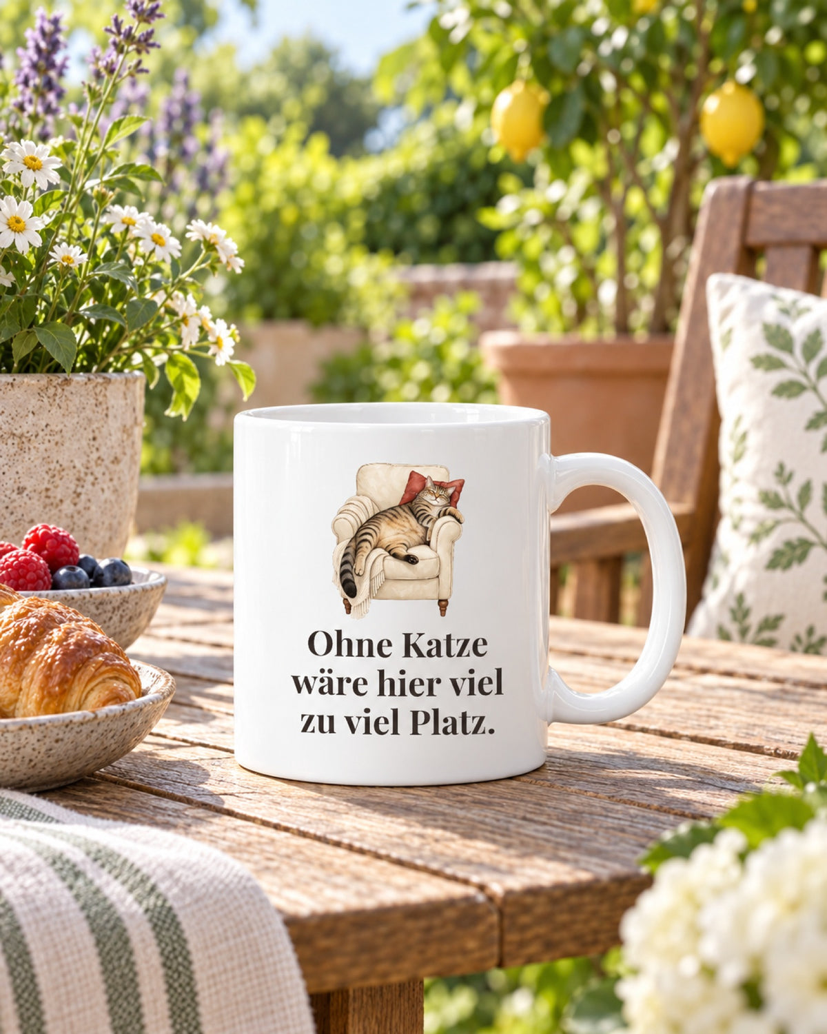Tasse „Ohne Katze wäre hier viel zu viel Platz.“ mit Katze im Sessel auf dem Gartentisch beim Frühstück
