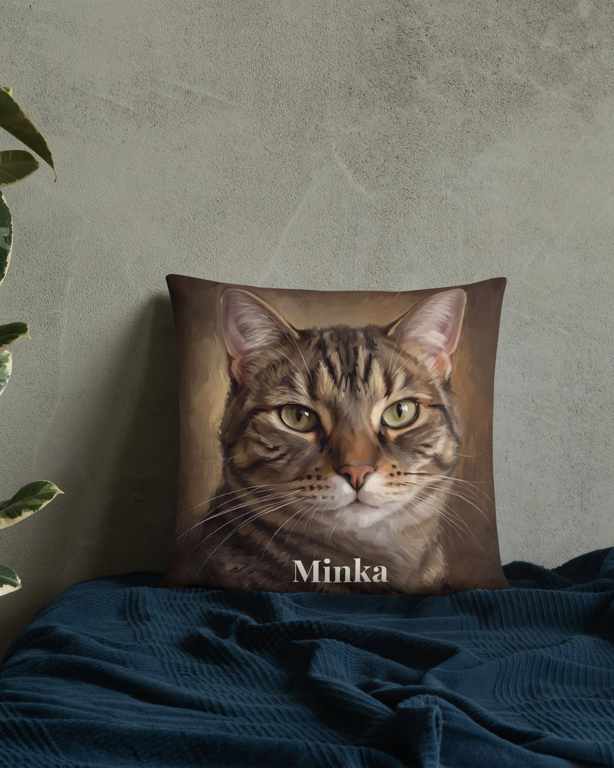 Kissen mit Katzenportrait im Ölgemälde-Stil und Namen Minka vor einer Wand