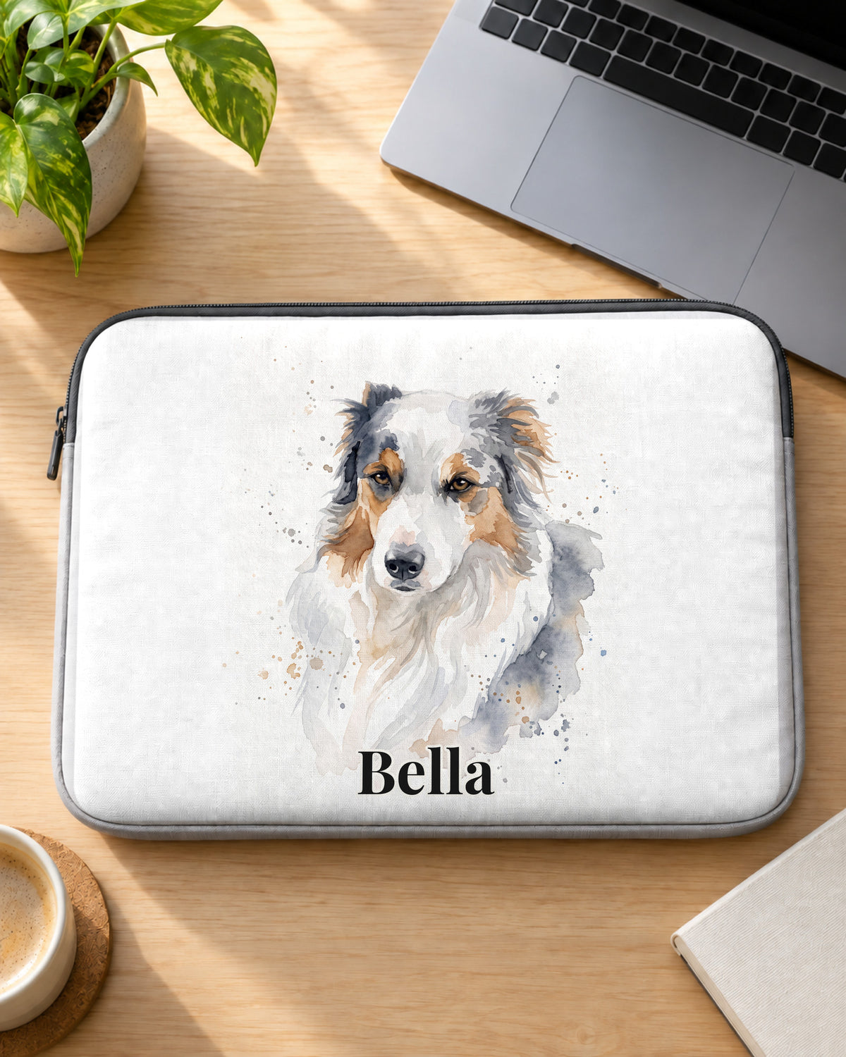 Laptophülle mit Hundeportrait im Aquarell-Stil und Namen Bella auf dem Schreibtisch
