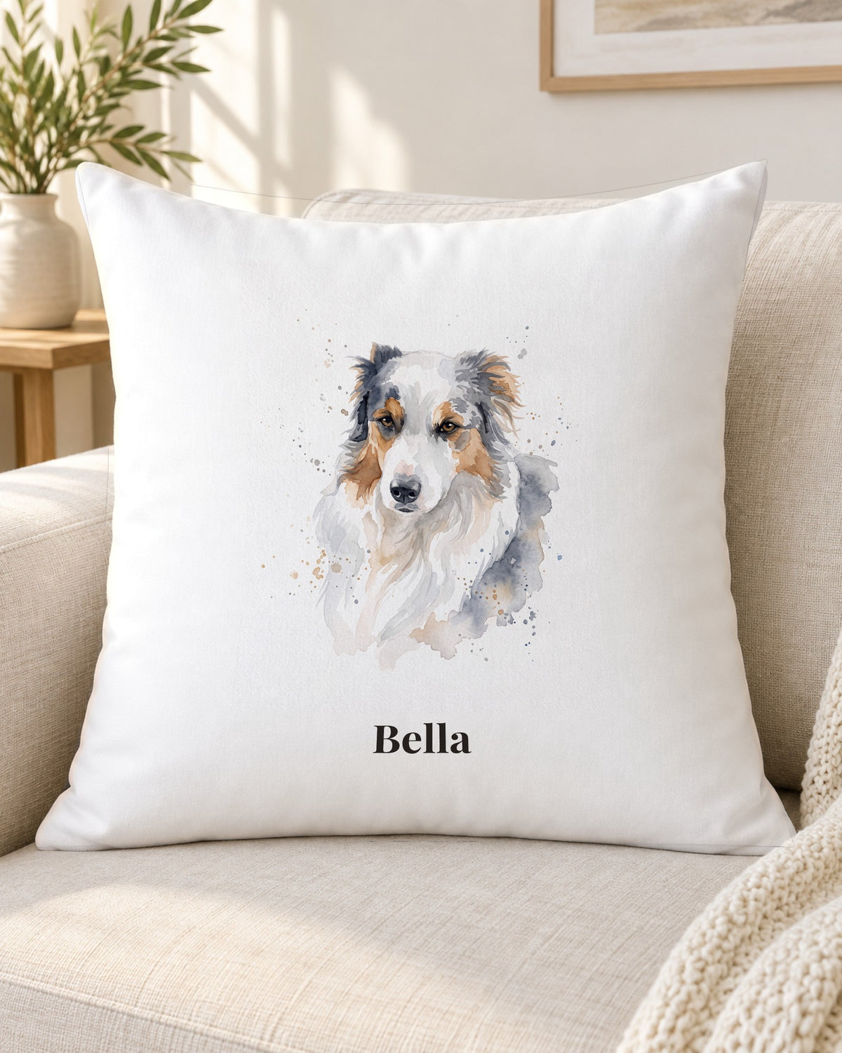 Kissen mit Hundeportrait im Aquarell-Stil und Namen Bella auf dem Sofa