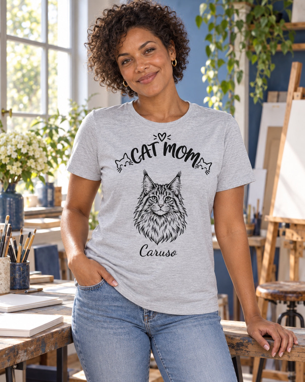 Frau im graumelierten Cat Mom T-Shirt mit Maine Coon Caruso als monochromer Linienzeichnung in einem blauen Atelier
