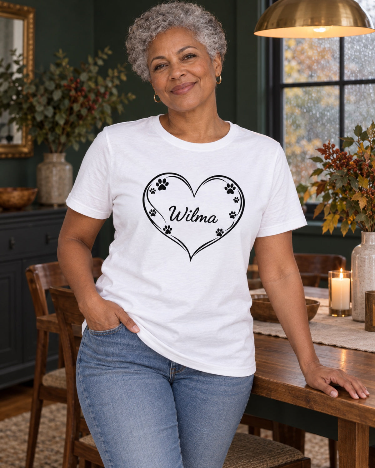 Frau im weißen T-Shirt mit Pfotenherz und Beispielname Wilma im dunkelgrünen Esszimmer