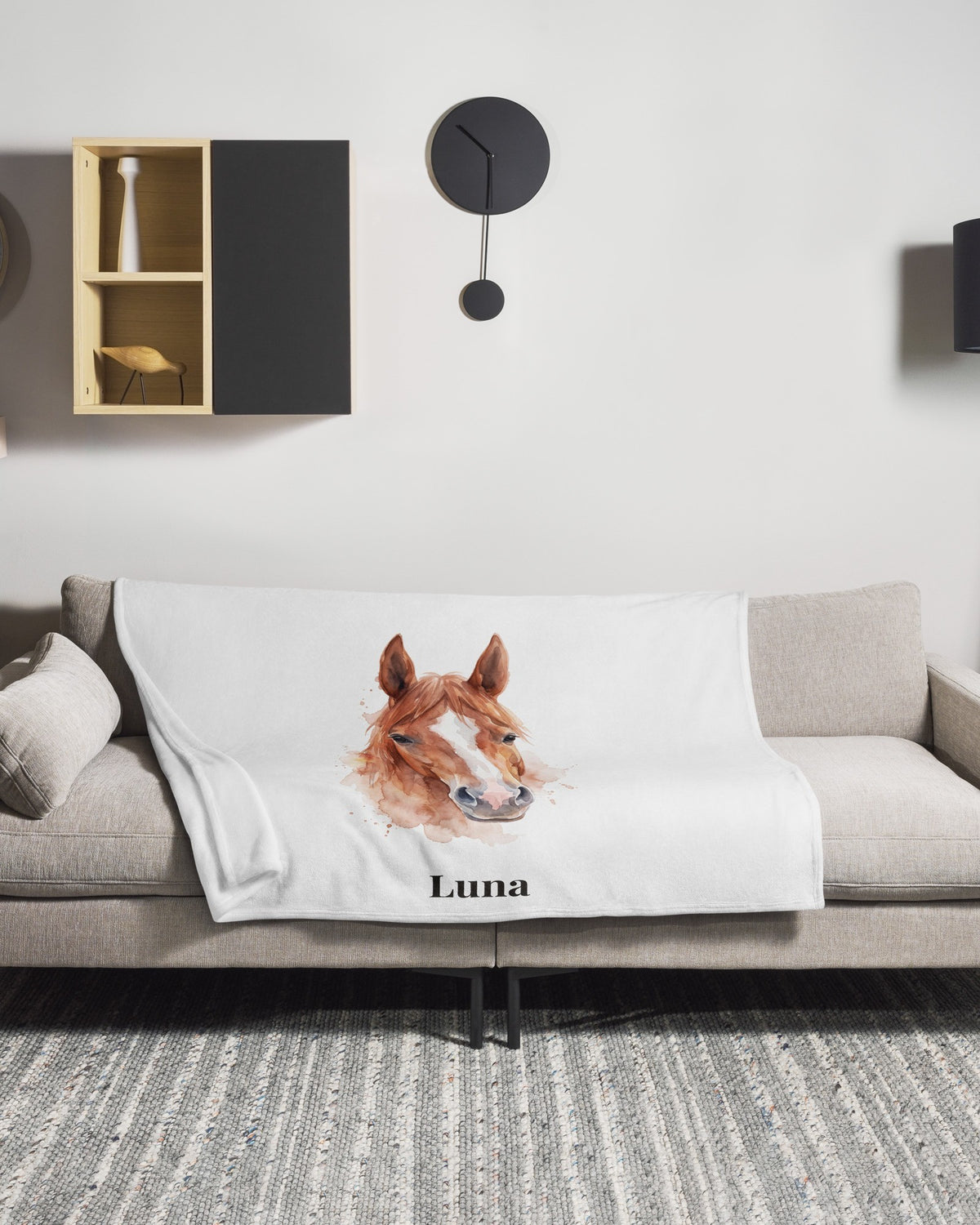 Kuscheldecke mit Pferdeportrait im Aquarell-Stil und Namen Luna auf dem Sofa