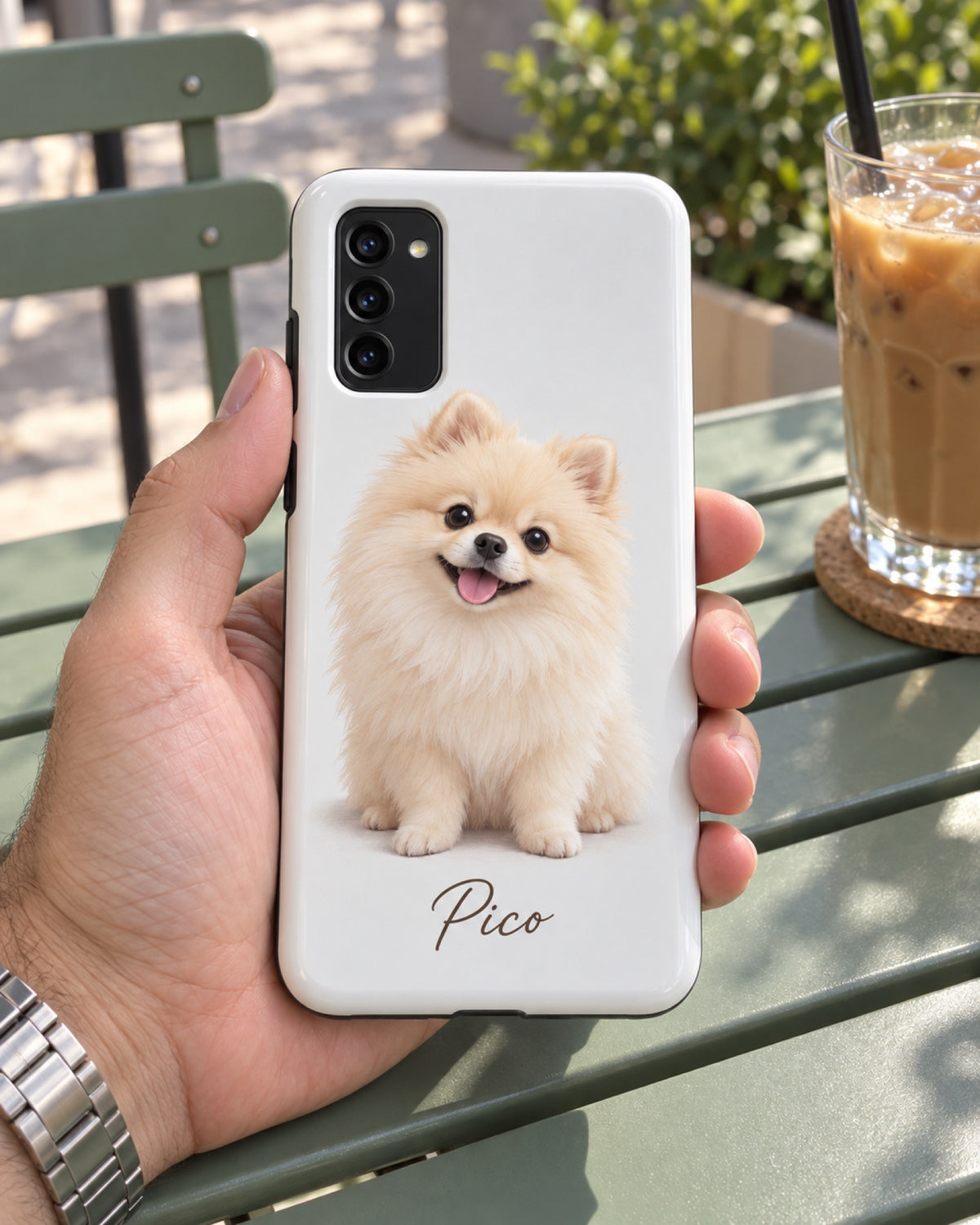 Samsung Galaxy S20 Hülle mit Zwergspitz im 3D-Cartoon-Stil und Namen Pico auf einer salbeigrünen Cafébank in einer Männerhand im Sommer