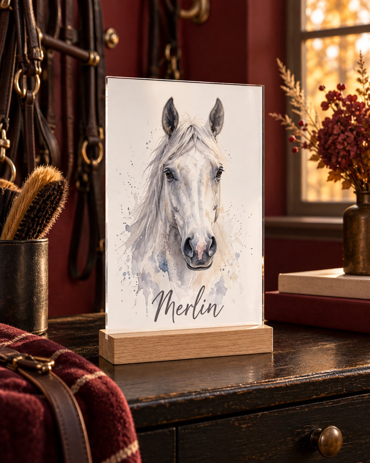 Acryl-Aufsteller mit Holzfuß und Schimmel Merlin als Aquarellportrait, Name Merlin in einer Lifestyle-Szene: dunkelrote Sattelkammer, Acryl steht auf einer schwarzen Holzkommode, warmes Herbstlicht